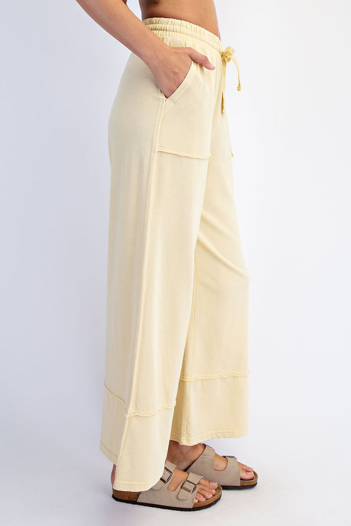 woman wearing light yellow wide-leg lounge pants with pockets and a drawstring waist