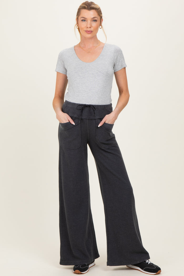 woman wearing a gray v-neck maternity top and dark wide-leg pants with pockets