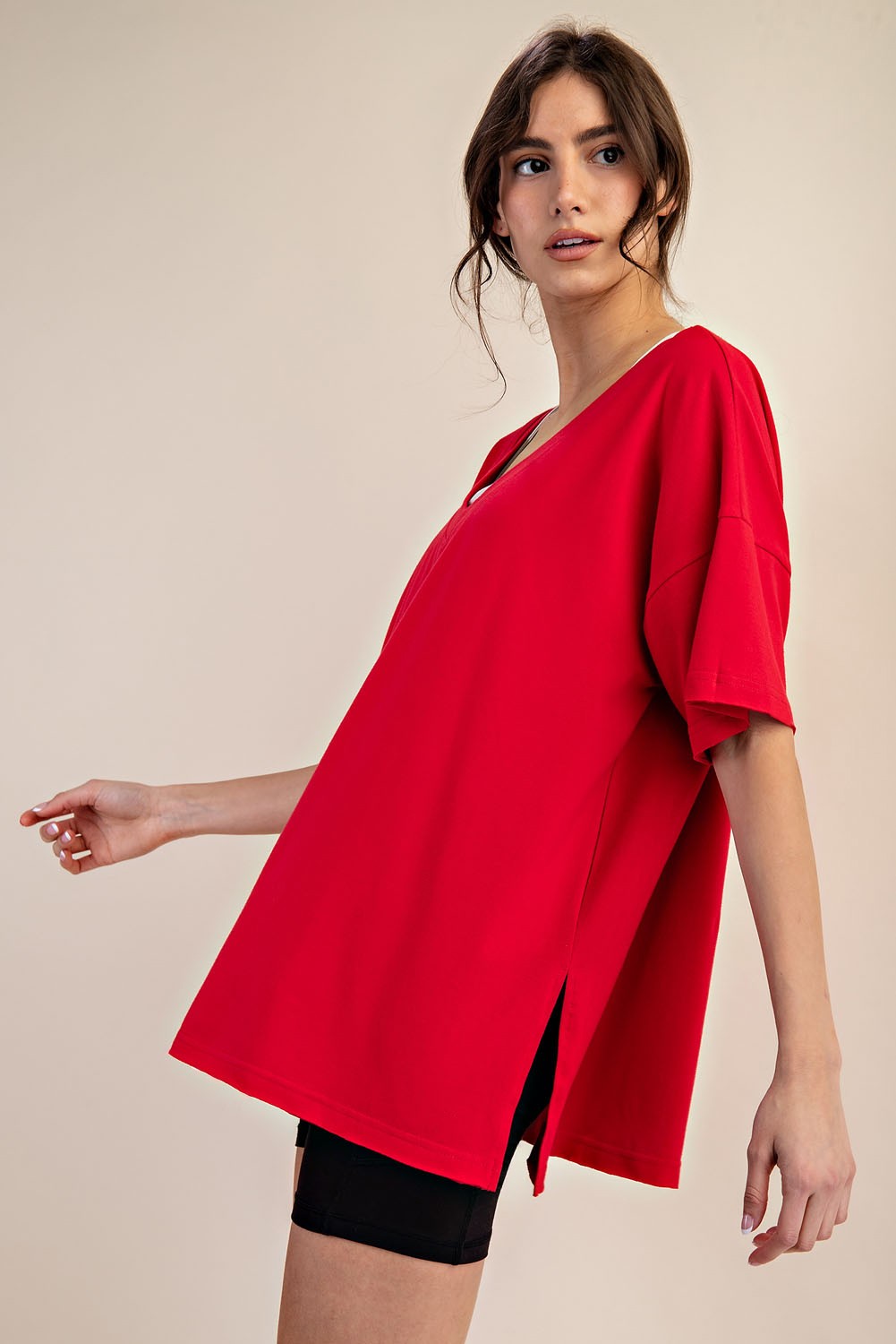 woman wearing a red oversized short sleeve top with side slits and paired with black shorts