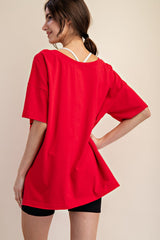 woman wearing a bright red oversized t-shirt with a relaxed fit and black shorts, viewed from the back
