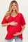 woman wearing a red short sleeve maternity top and holding her baby bump