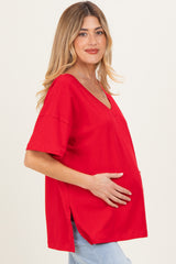 woman wearing a red short sleeve maternity top and holding her baby bump