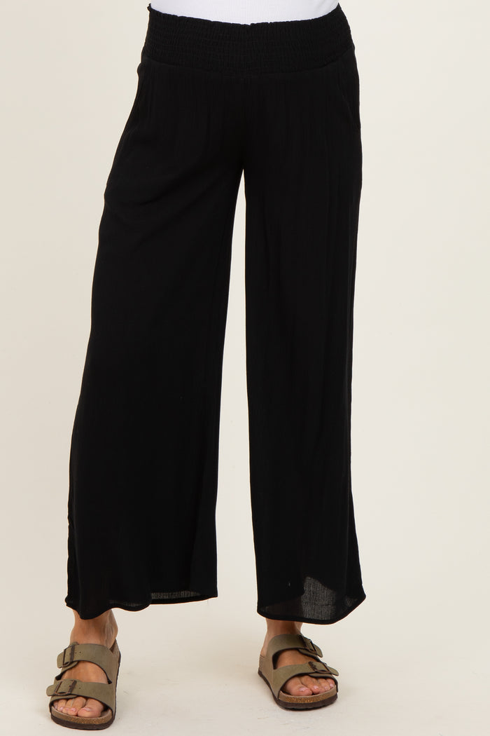 woman wearing black loose-fitting maternity pants with a smocked waistband and wide legs