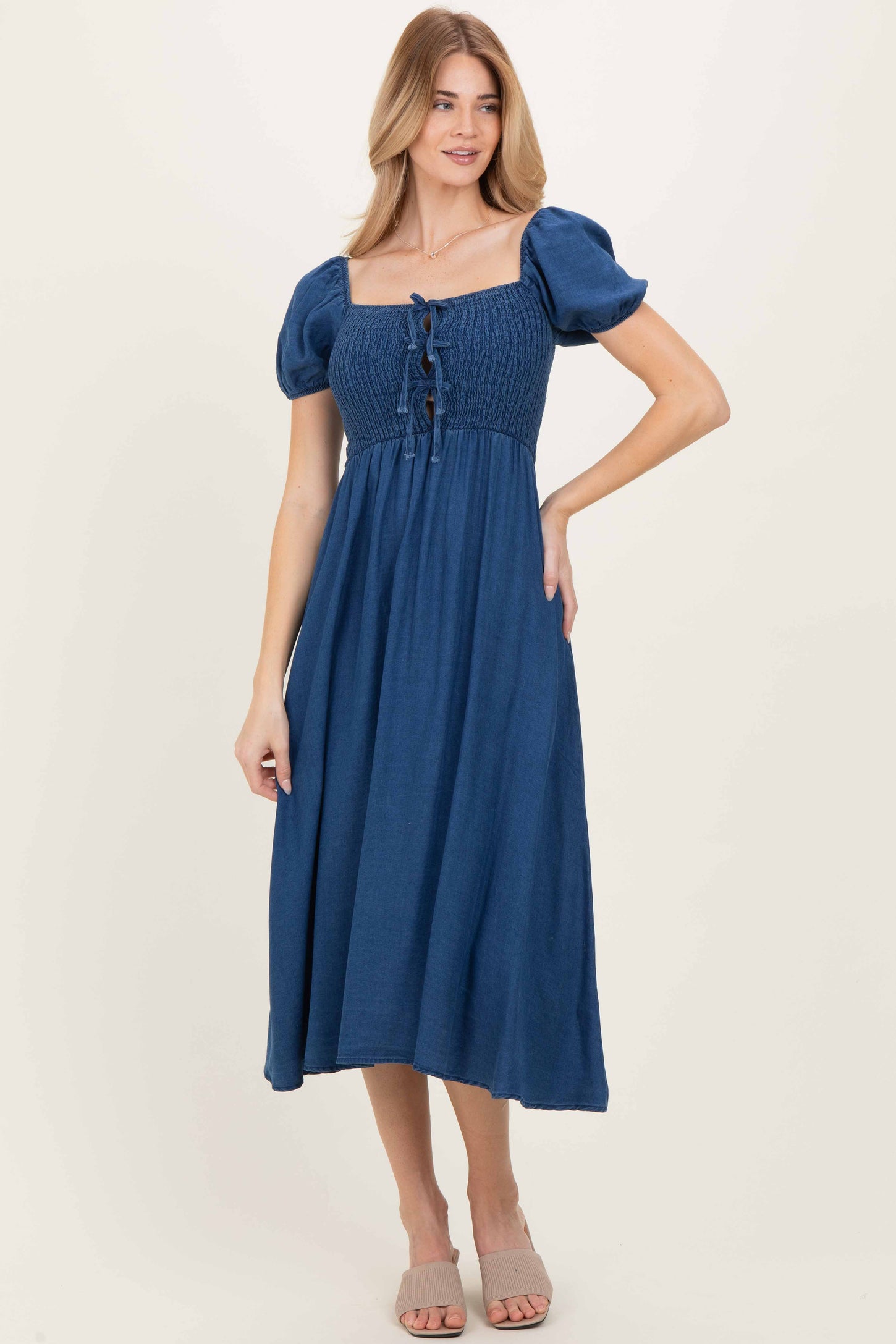 woman wearing a navy blue square neck midi dress with puff sleeves and button details