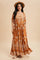 woman wearing a rust brown floral maxi dress with puff sleeves and a square neckline, styled with a hat