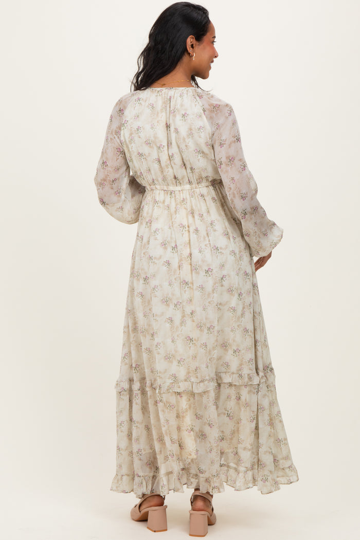 woman wearing a floral patterned long sleeve maternity dress with a tiered skirt and elastic waist, showing a baby bump
