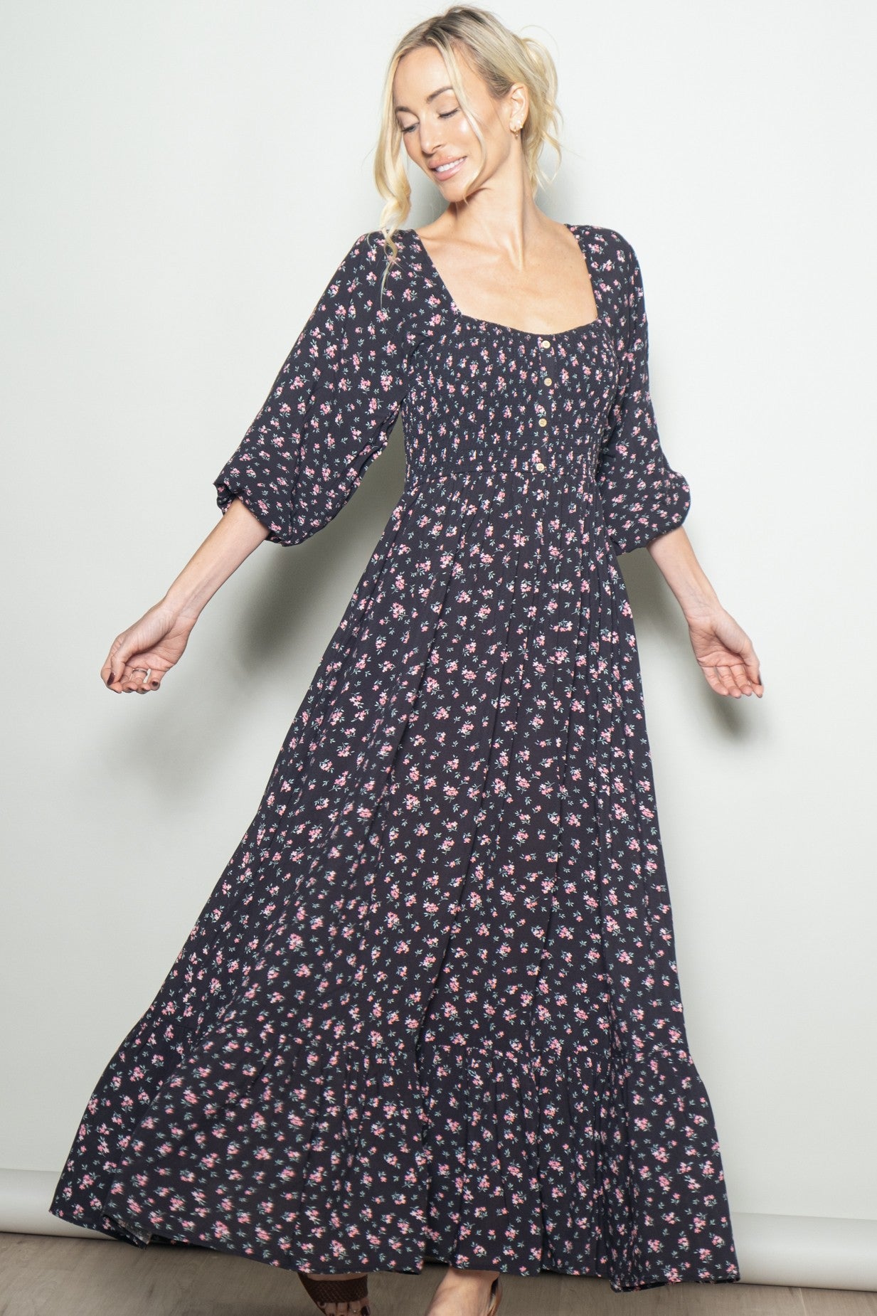 woman wearing a black floral maxi dress with puff sleeves and a fitted bodice, spinning with a joyful expression