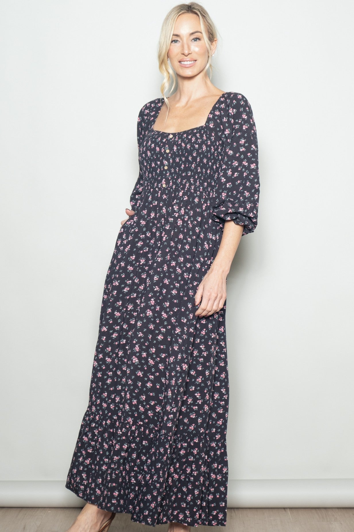 woman wearing a black floral maxi dress with short puff sleeves and a square neckline