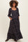 woman wearing a black floral maternity maxi dress with three-quarter sleeves and pockets, showcasing her baby bump
