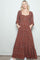 woman wearing a rust floral maxi dress with square neckline and pockets, styled with white sneakers