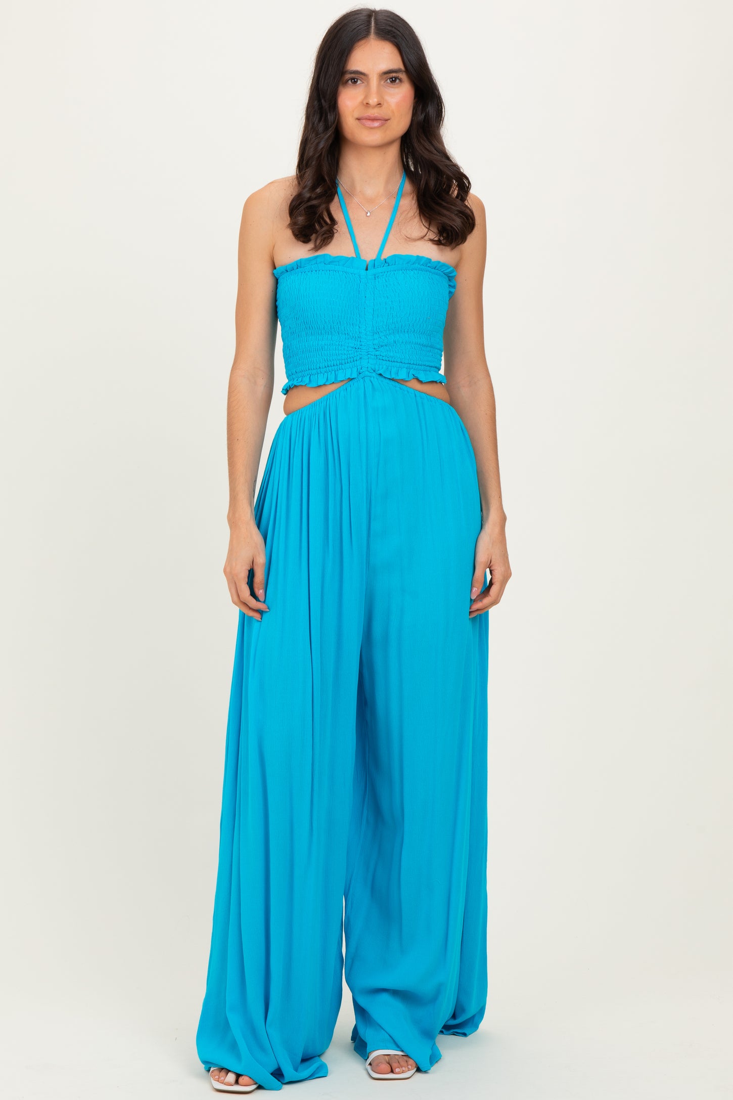 woman wearing a bright blue strapless jumpsuit with smocked bodice and cut-out details