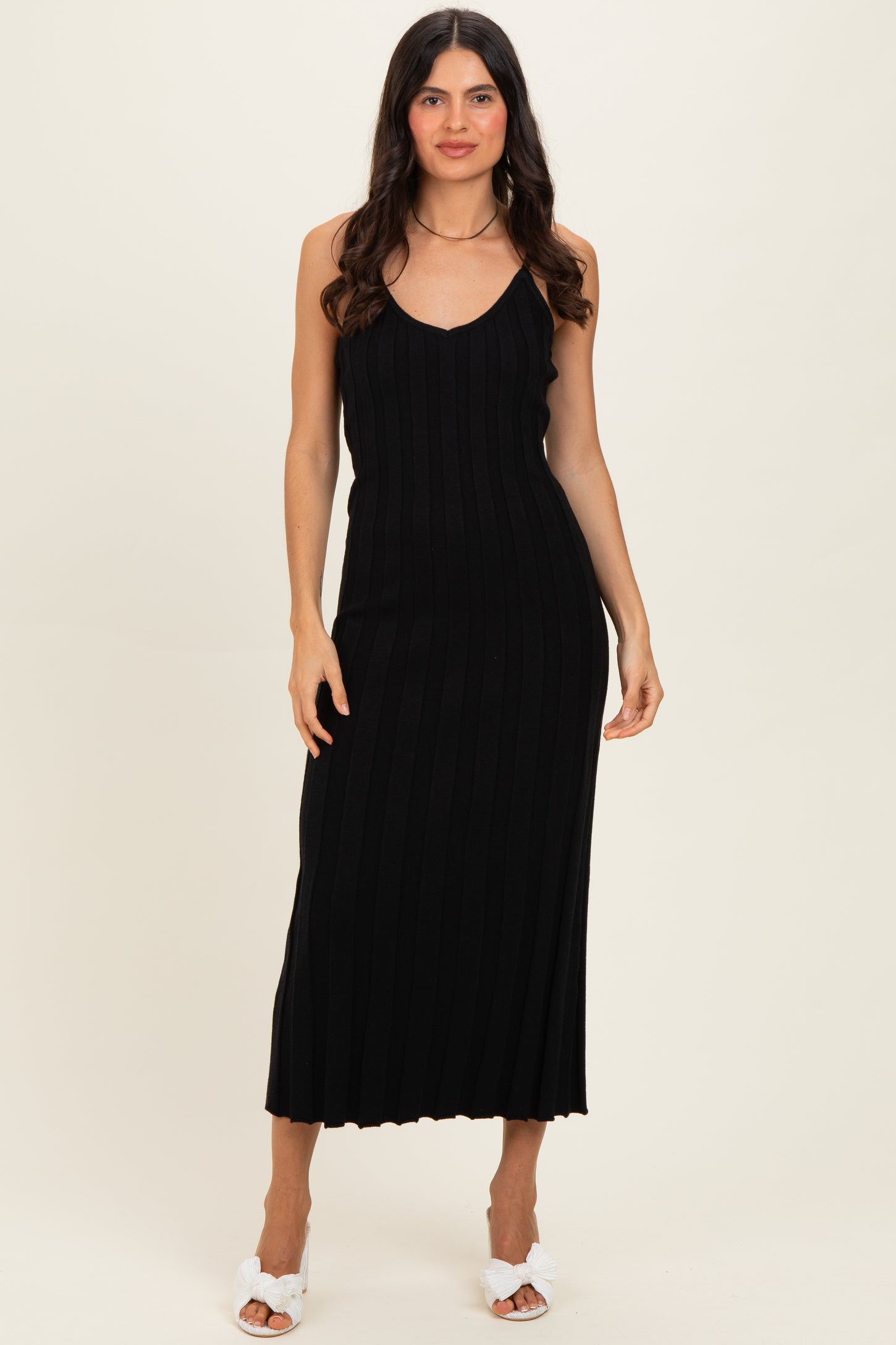woman wearing a black ribbed knit midi dress with spaghetti straps and a fitted silhouette