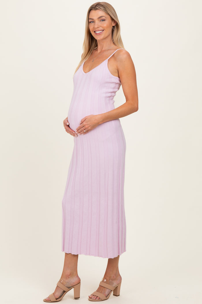 woman wearing a light pink ribbed maternity dress, showcasing her baby bump, with a fitted silhouette and midi length