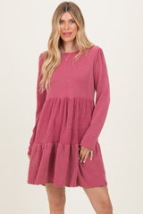 woman wearing a pink ribbed long sleeve dress with a tiered skirt and relaxed fit