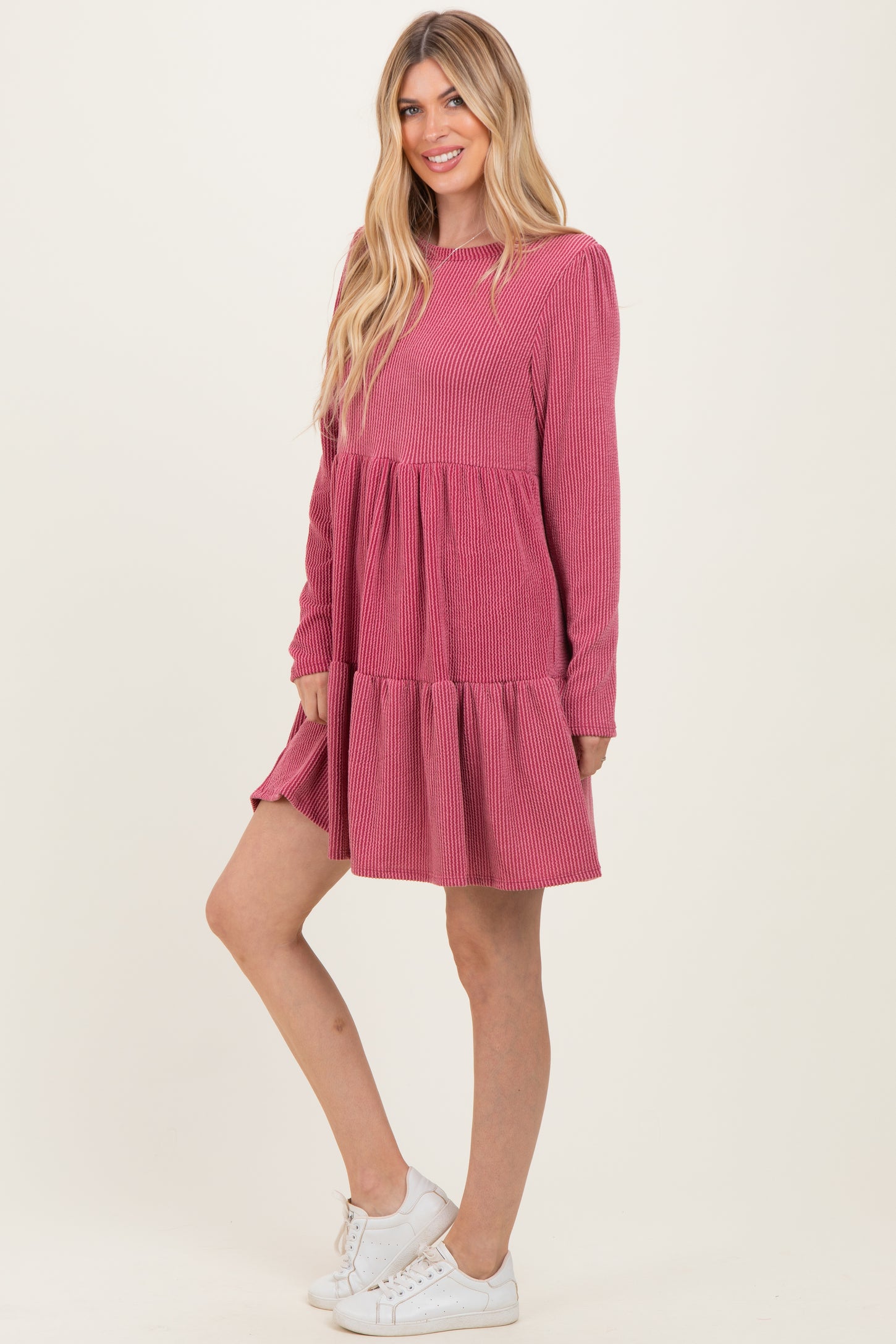 woman wearing a pink striped long sleeve tiered dress and white sneakers