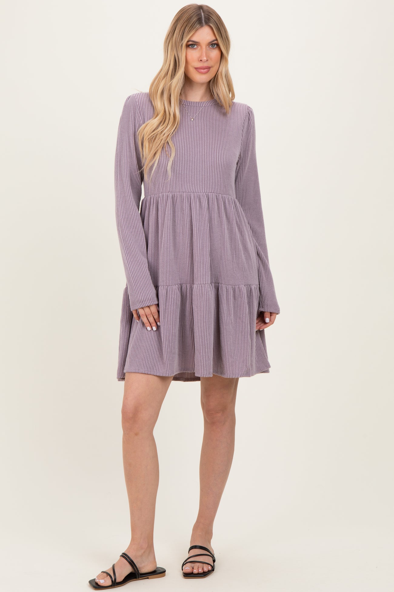 woman wearing a lavender and white striped long sleeve tiered mini dress with a relaxed fit and sandals