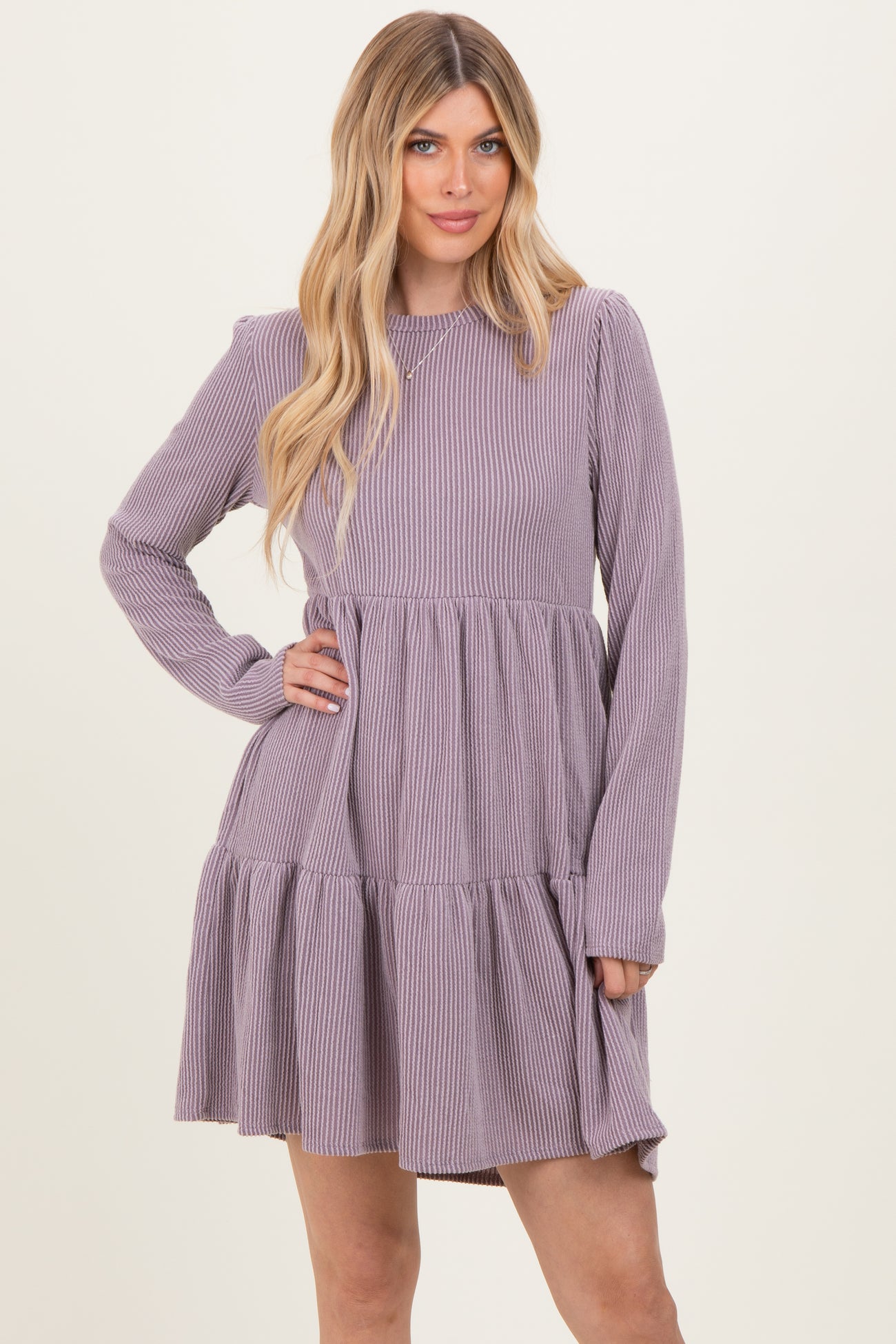 woman wearing a purple ribbed long sleeve dress with a tiered ruffled skirt