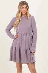 woman wearing a purple ribbed long sleeve dress with a tiered ruffled skirt