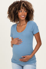 woman wearing a soft blue short sleeve maternity top and holding her baby bump
