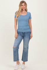 woman wearing a light blue short sleeve scoop neck top and distressed light wash jeans
