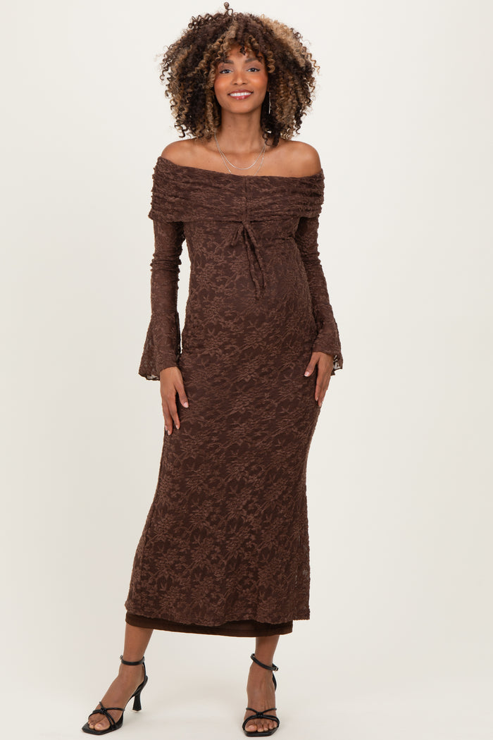 woman wearing a brown off-shoulder lace maternity dress with bell sleeves and a visible baby bump