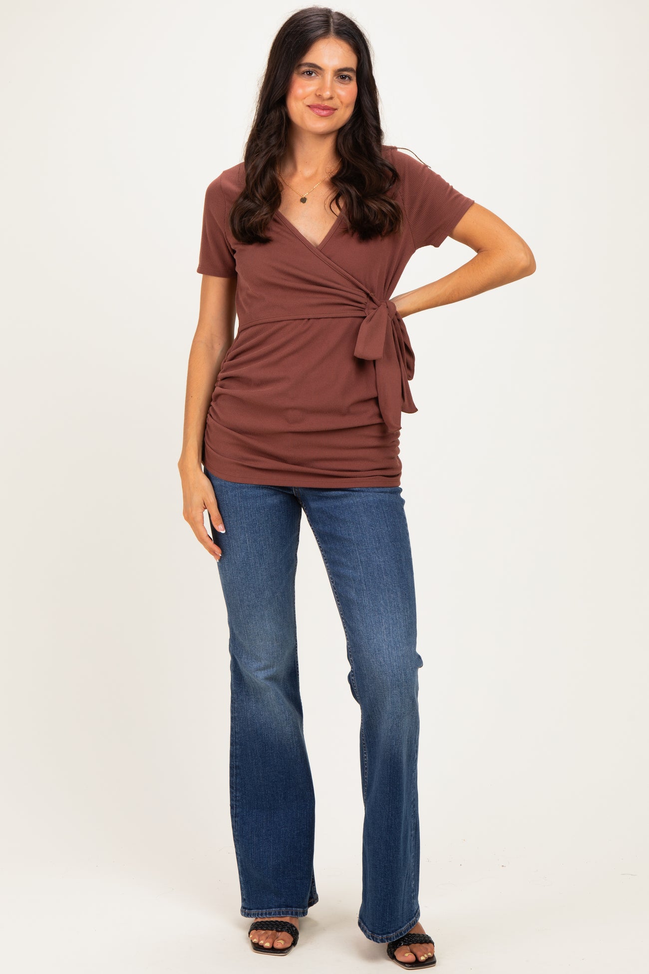 woman wearing a brown wrap top with a tie detail and blue flared jeans