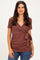 woman wearing a rust-colored short sleeve wrap top with a tie detail at the waist and jeans