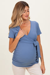 woman wearing a blue ribbed maternity top with a tie detail, showcasing her baby bump