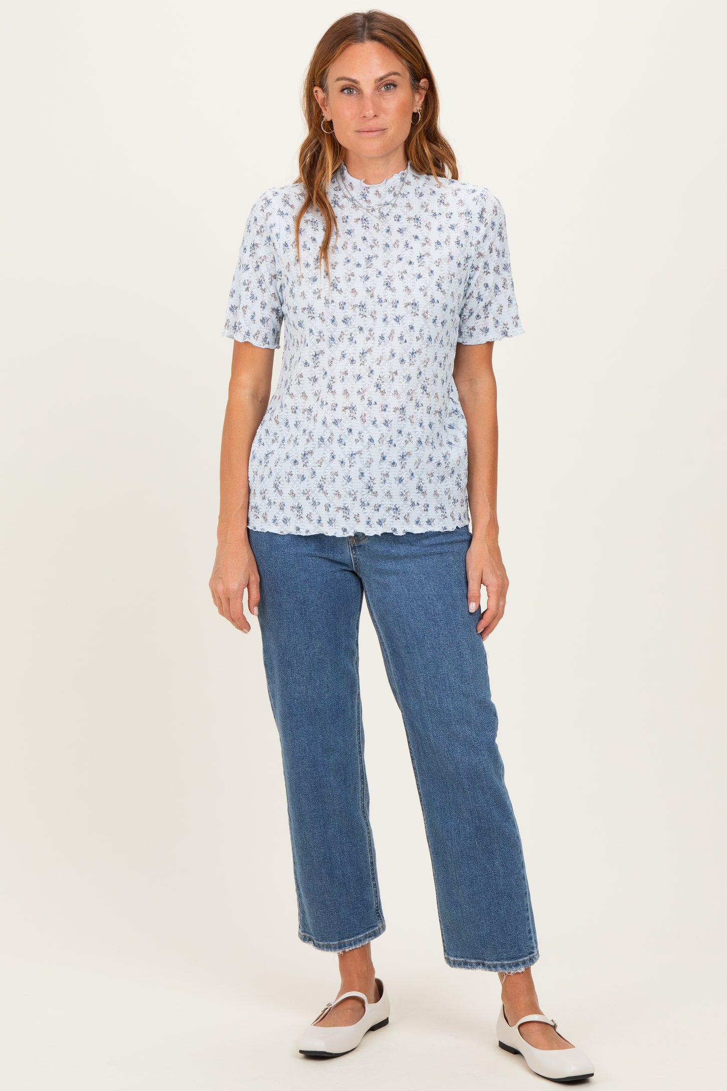 woman wearing a light blue floral short sleeve blouse and high-waisted denim jeans
