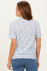woman wearing a light blue short sleeve blouse with floral print and a back view, paired with denim jeans