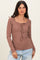 woman wearing a brown ribbed long sleeve top with a square neckline and tie detail, paired with light blue jeans