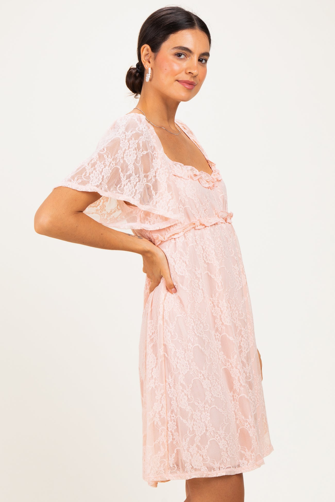 woman wearing a light pink lace dress with a ruffled neckline and short sleeves