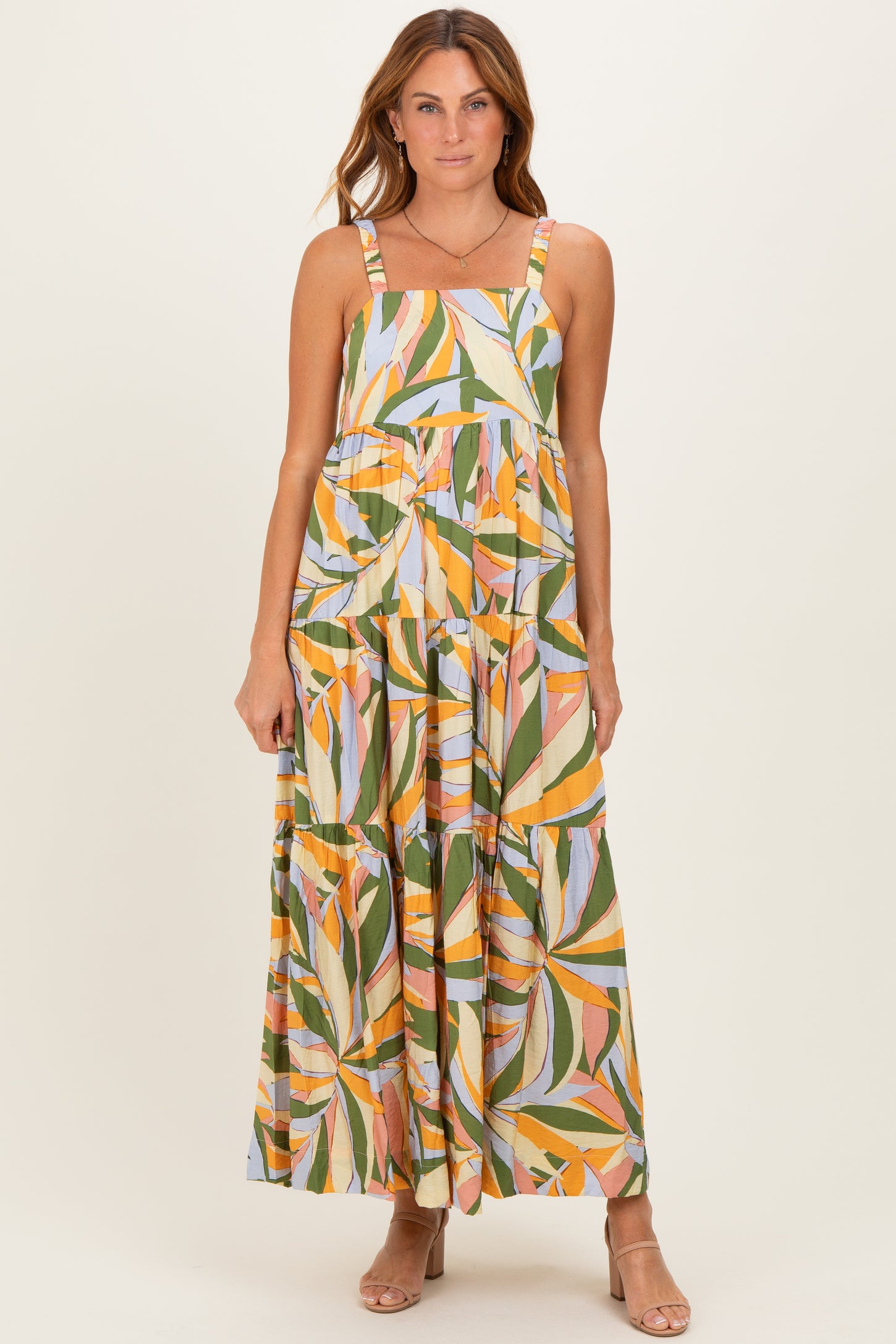 woman wearing a colorful floral print maxi dress with adjustable straps and a tiered design