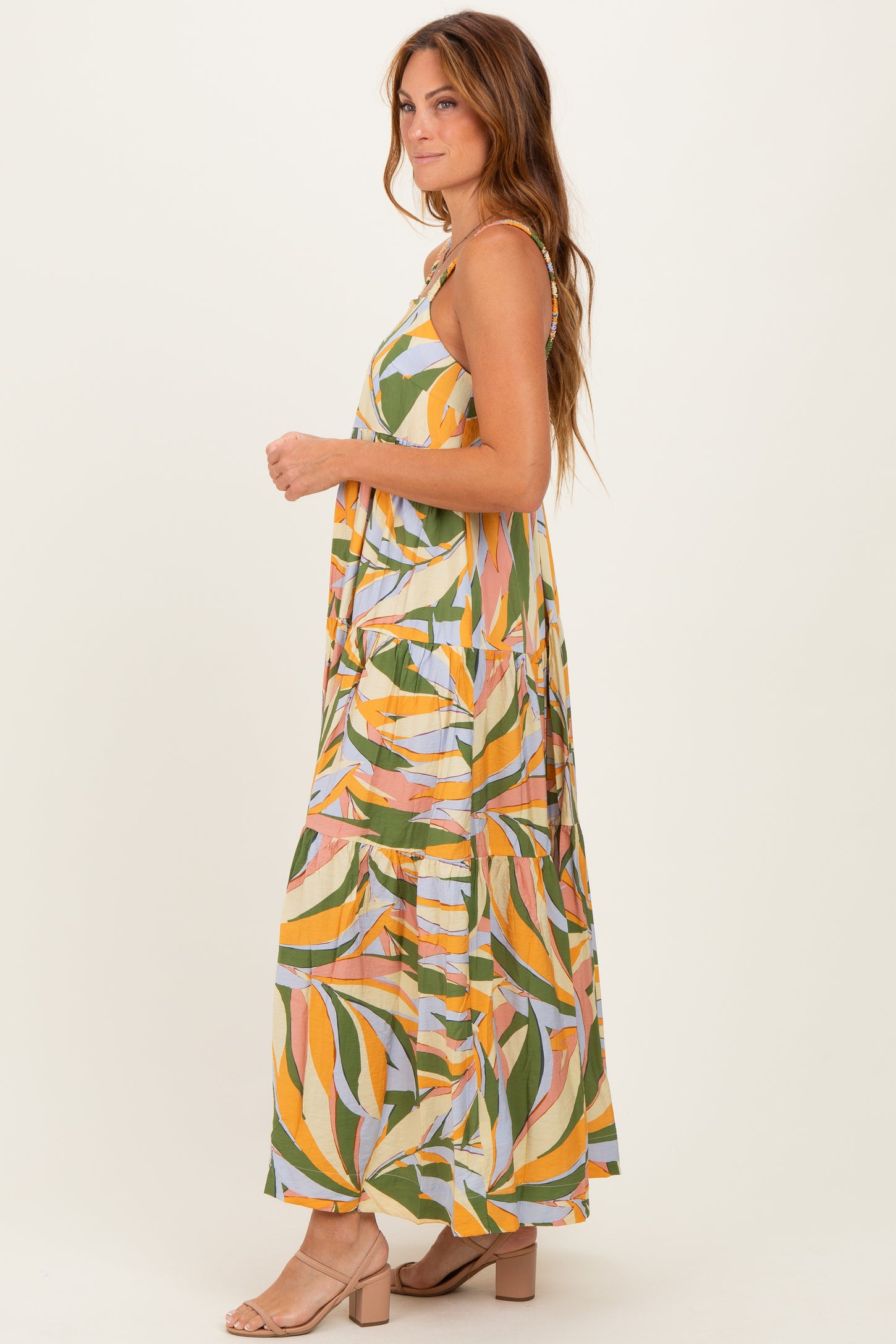 woman wearing a multicolored leaf print maxi dress with spaghetti straps and a flowy design