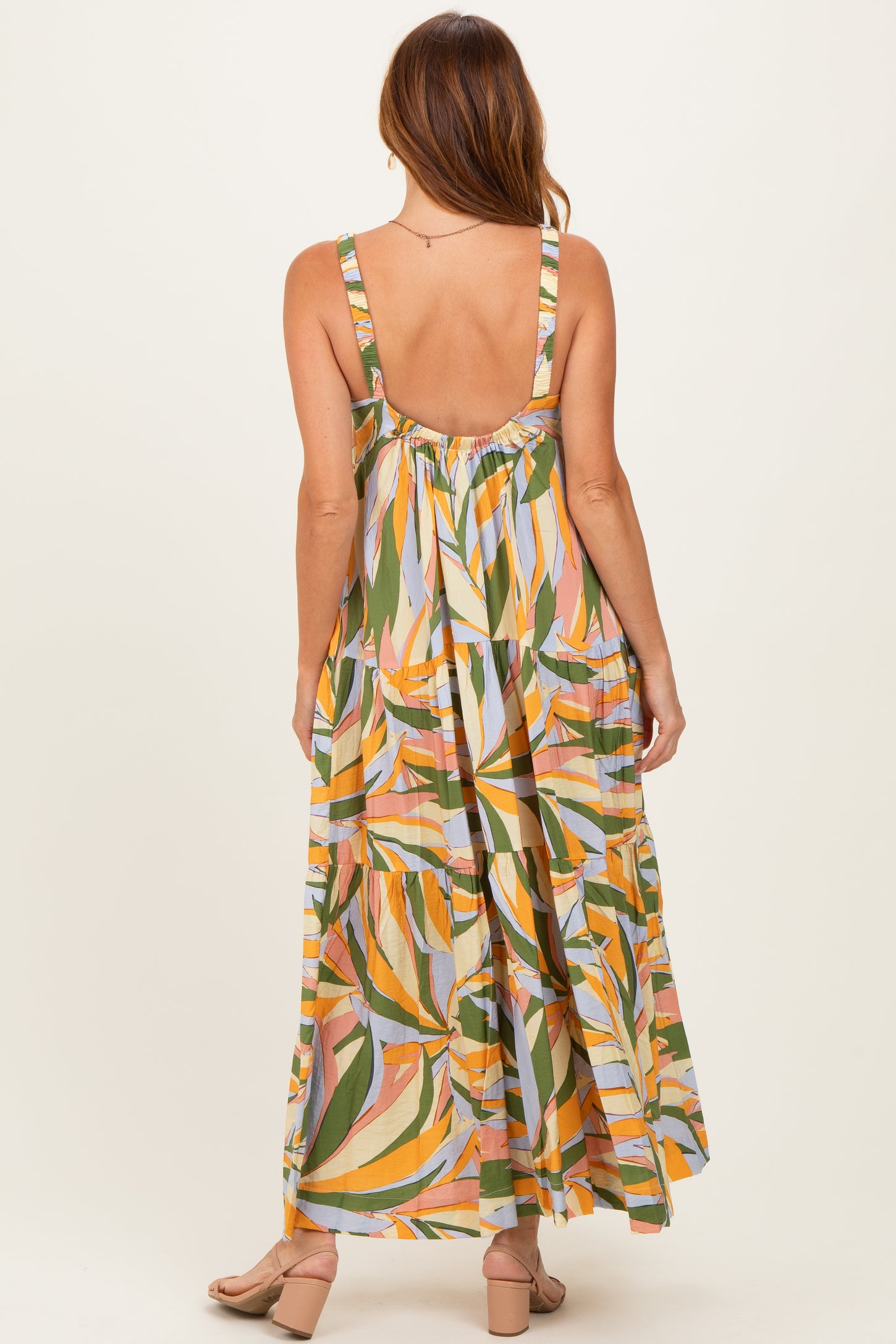 woman wearing a colorful leafy maxi dress with a backless design and flowing skirt