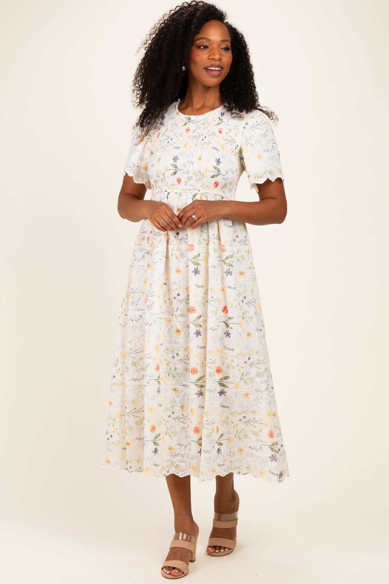 woman wearing a light floral pattern midi dress with short sleeves and a fitted waist, standing on a neutral background