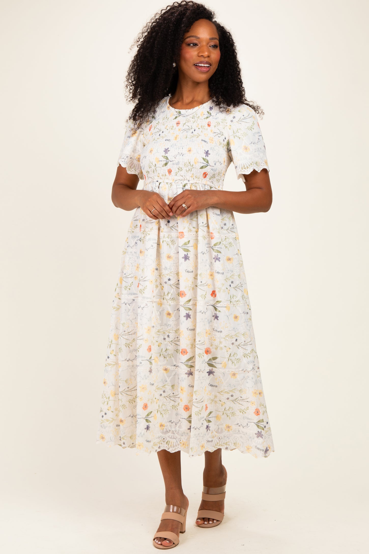 woman wearing a light floral pattern midi dress with short sleeves and a fitted waist, standing on a neutral background