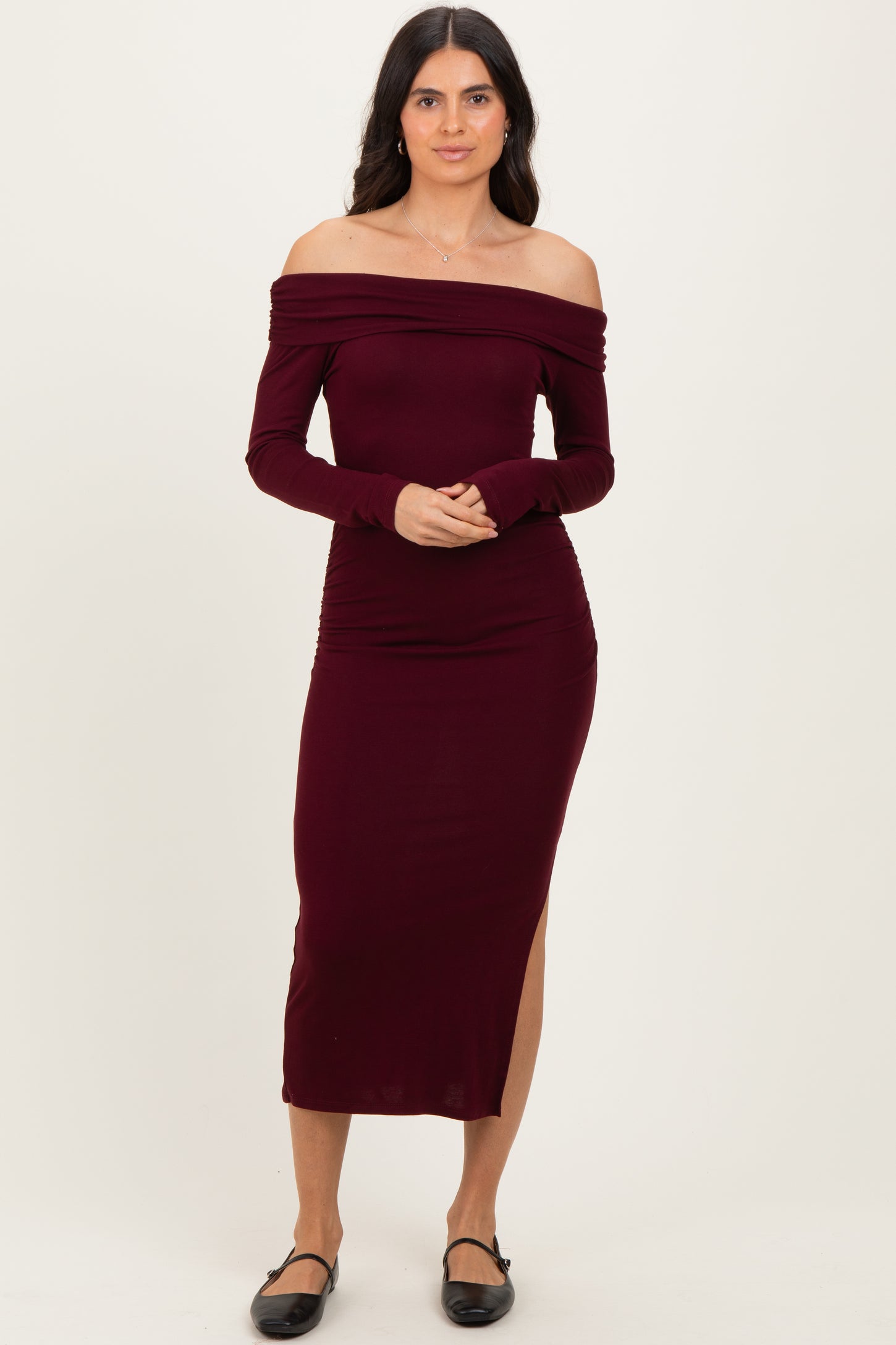 woman wearing a burgundy off-the-shoulder bodycon midi dress with side slit and long sleeves
