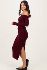 woman wearing a burgundy off-the-shoulder long sleeve dress with side ruching and a slit