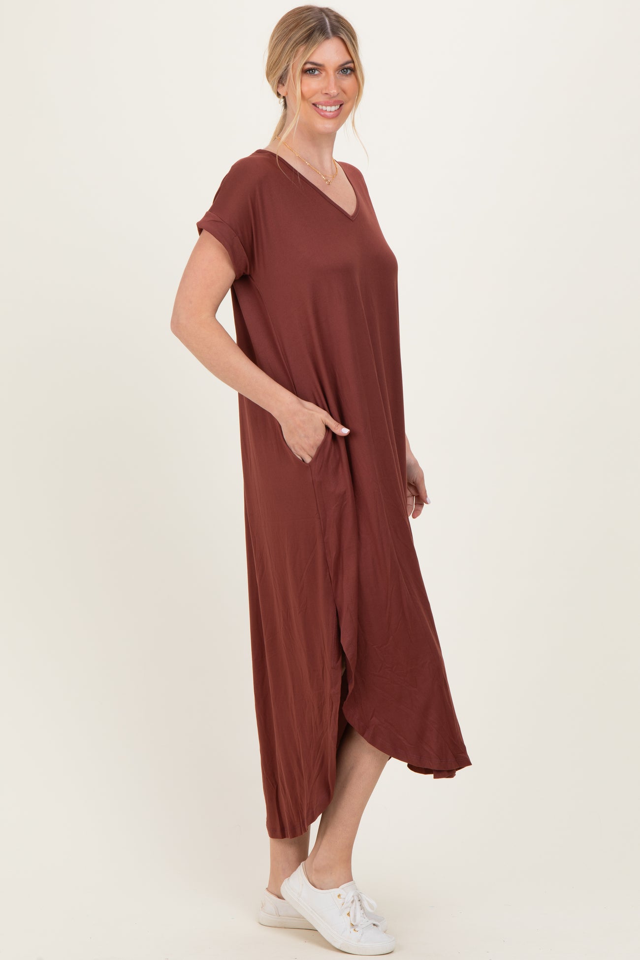 woman wearing a rust colored short sleeve maxi dress with pockets and a v-neckline