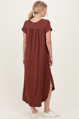 woman wearing a rust-colored maxi dress with short sleeves and a relaxed fit, showing a side slit