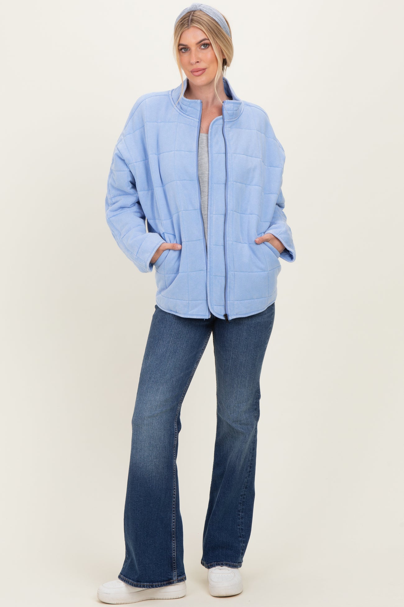 woman wearing a light blue quilted jacket with pockets, paired with a gray top and flared jeans