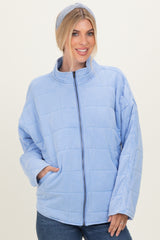 woman wearing a light blue quilted jacket with a high collar and side pockets, styled with a matching headband