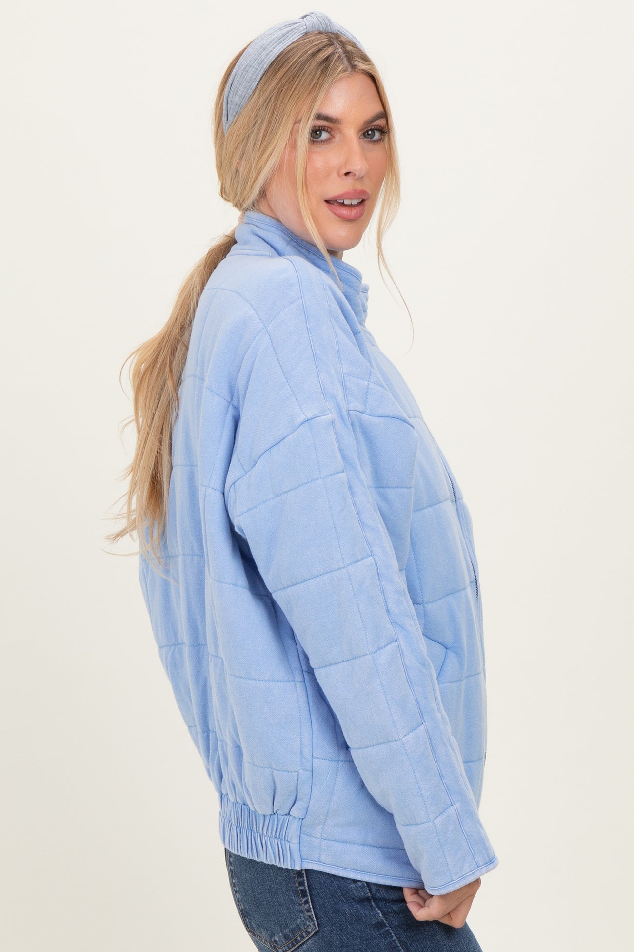 woman wearing a light blue quilted pullover jacket with a high collar and elastic waistband