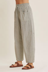 woman wearing black and white striped relaxed fit pants with elastic waistband and side pockets paired with brown sandals