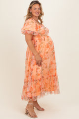 woman wearing a floral peach maternity dress with puff sleeves and ruffled hem, highlighting her baby bump