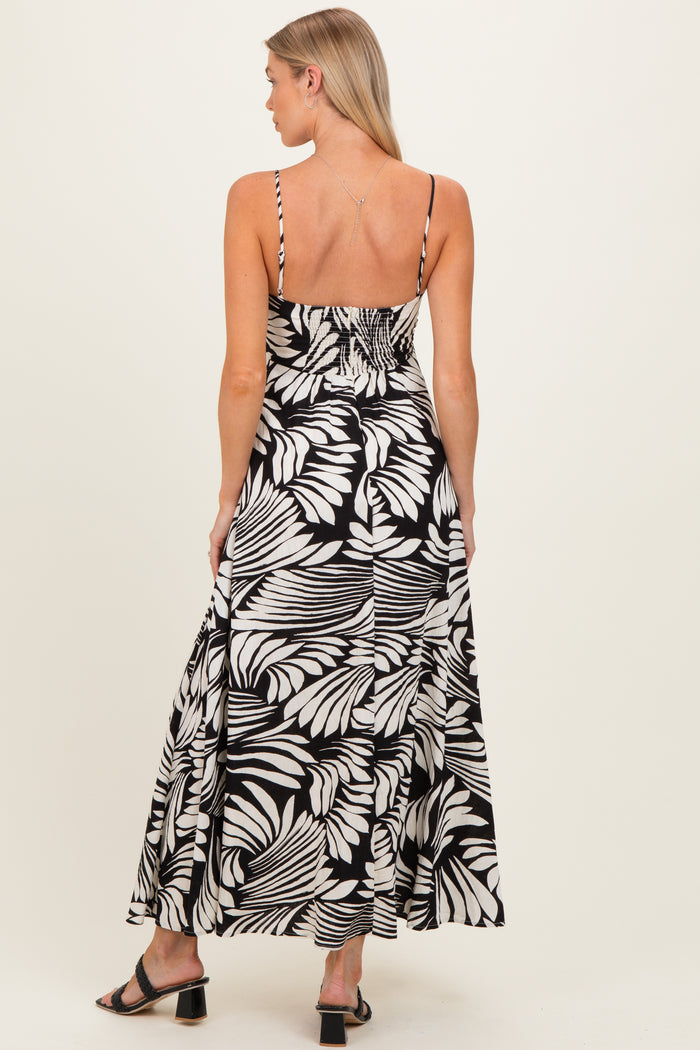 woman wearing a black and white floral maternity maxi dress with spaghetti straps and a fitted bodice