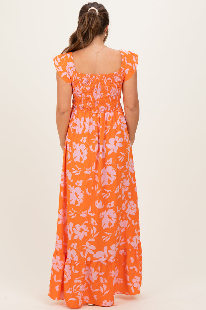 woman wearing an orange floral maternity maxi dress with short ruffled sleeves and a smocked back detail