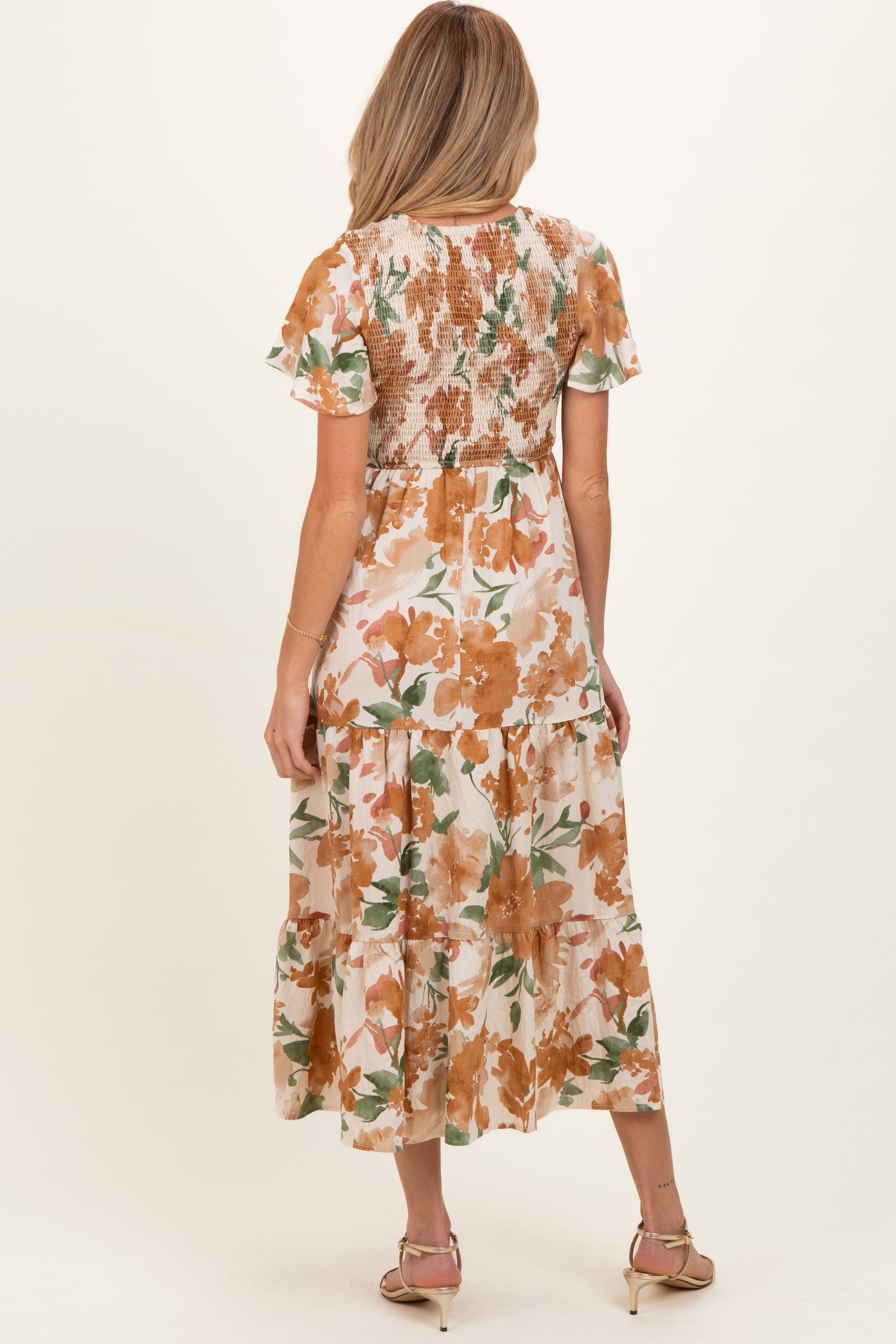 woman wearing a floral maternity maxi dress with short ruffled sleeves and a smocked back, showing off her baby bump