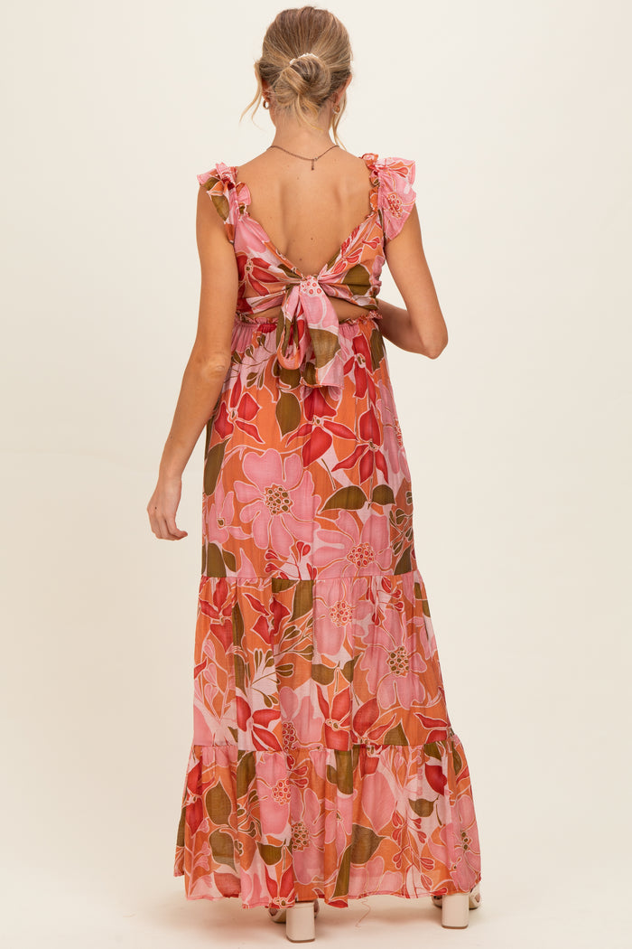 woman wearing a pink floral maternity maxi dress with ruffled sleeves and a tied open back